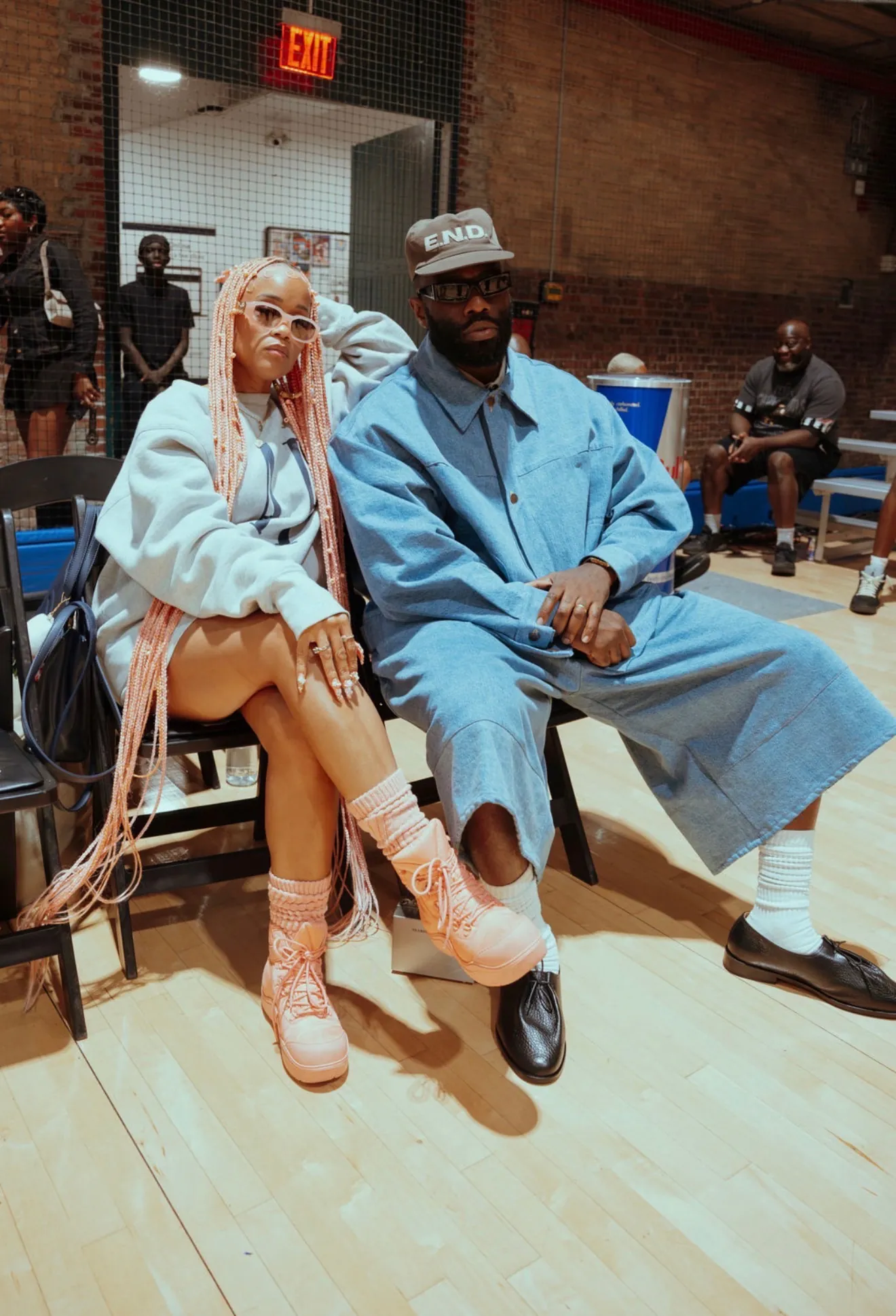 Two guests in streetwear seated courtside