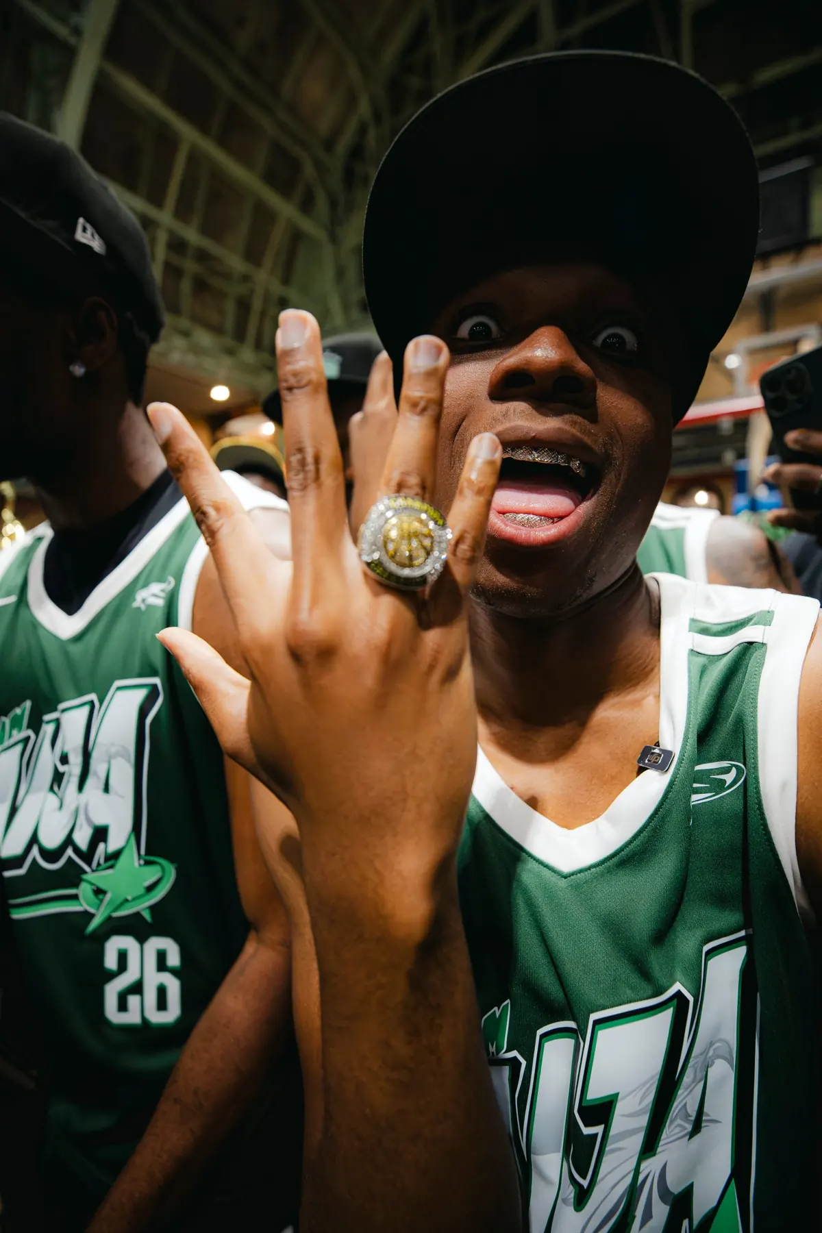 A player in a green jersey showing off a championship ring