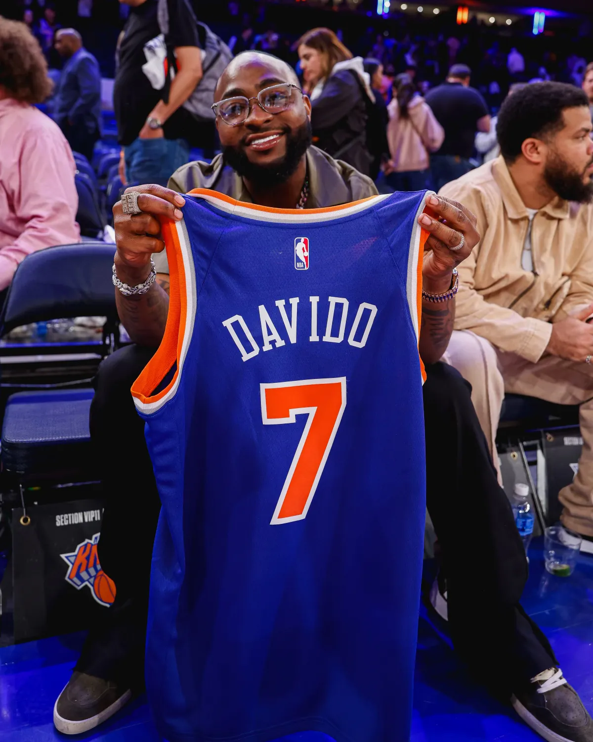 Davido courtside at Madison Square Garden holding a Knicks jersey with his name