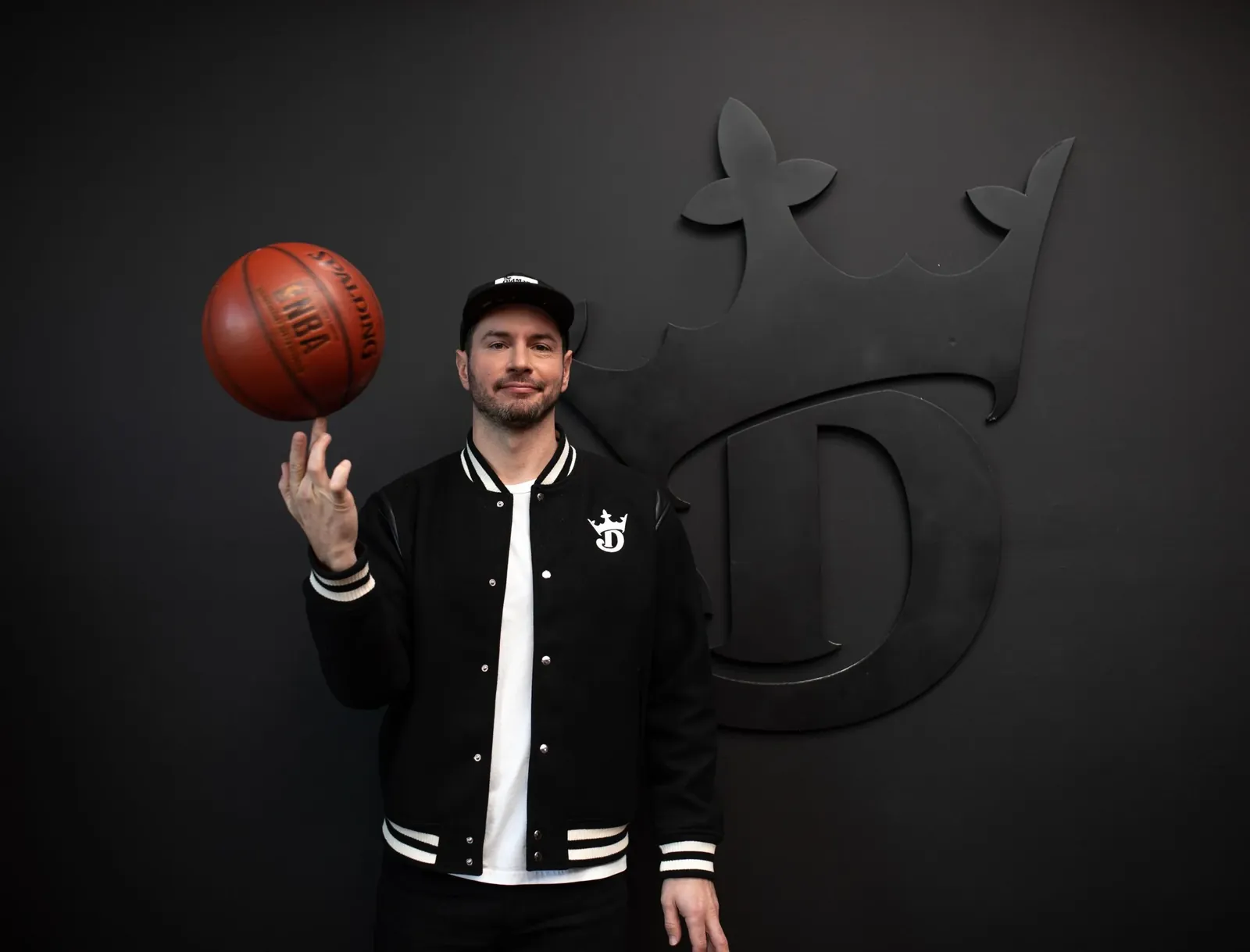 JJ Redick spinning a basketball in front of the DraftKings logo during a content shoot